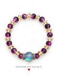 Handmade bracelet with deep purple beads, champagne-gold crystals and a glittering galaxy centre bead